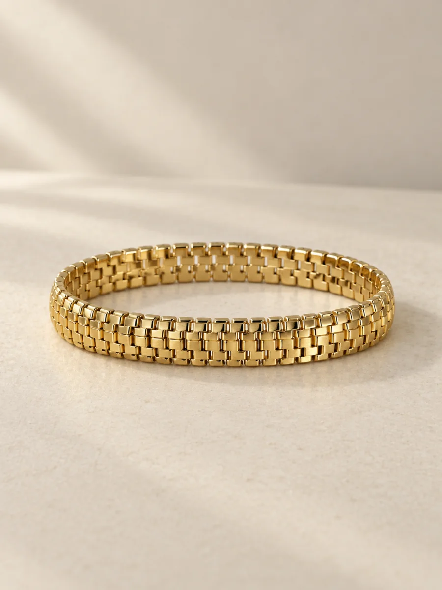 Pulseira dourada articulada com elos retangulares em fundo bege