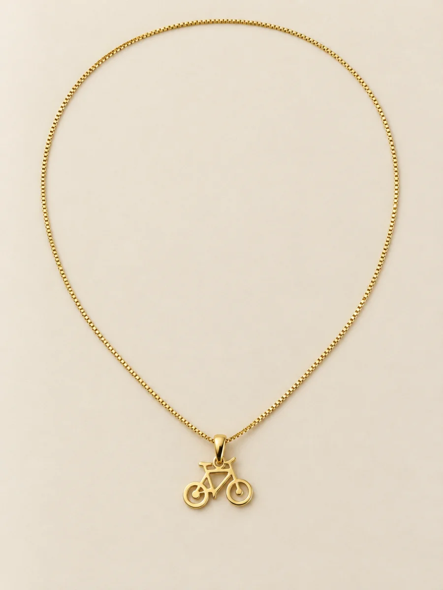 Colar dourado com bicicleta sobre fundo bege