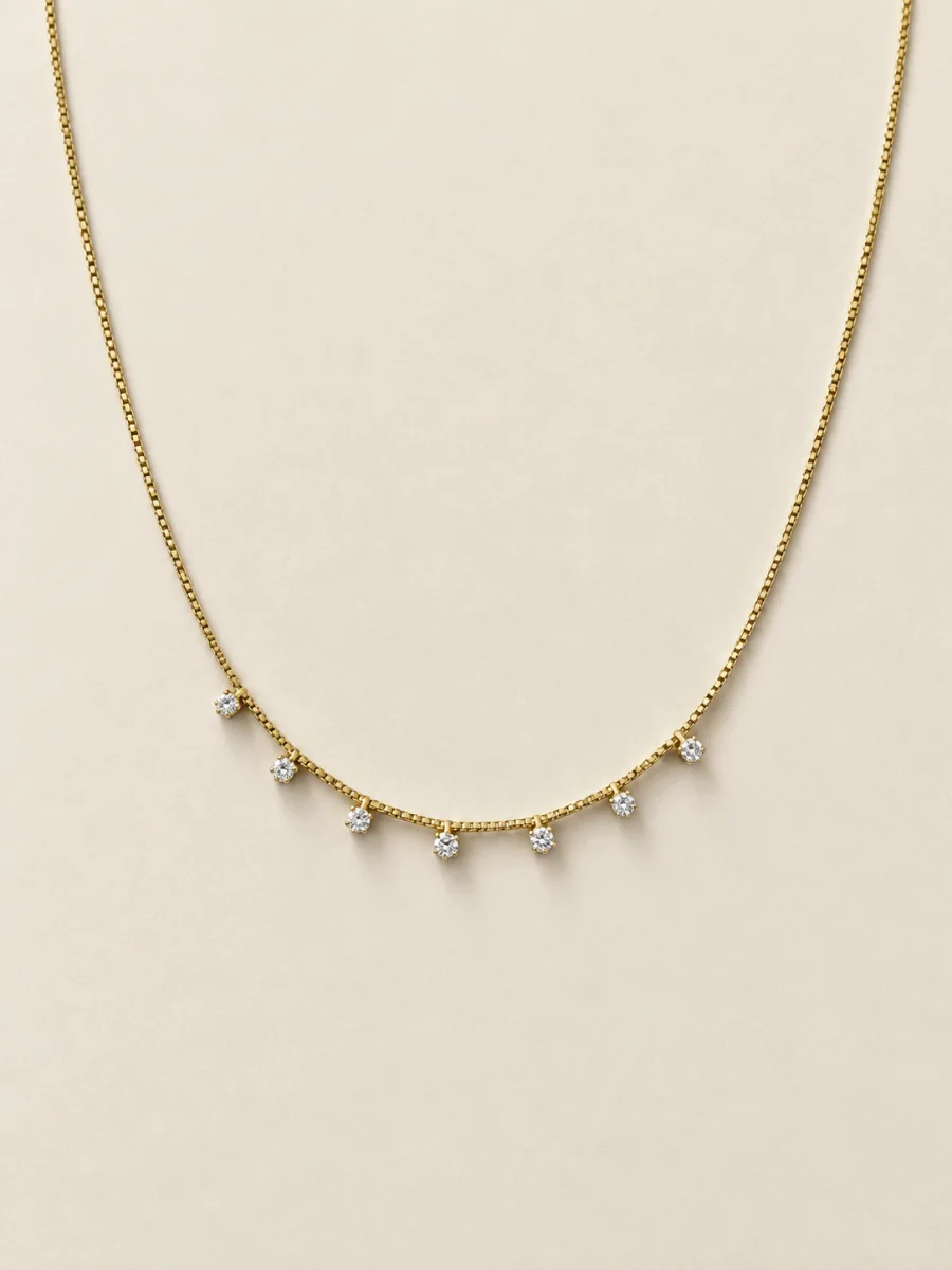 Colar dourado com pedras claras pendentes sobre fundo bege