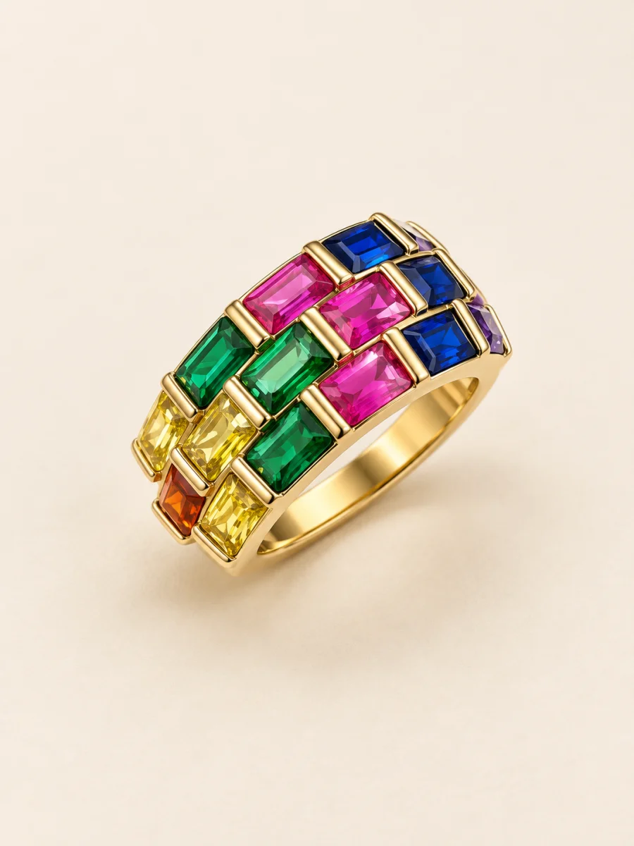 Anel dourado com faixas de pedras coloridas sobre fundo bege