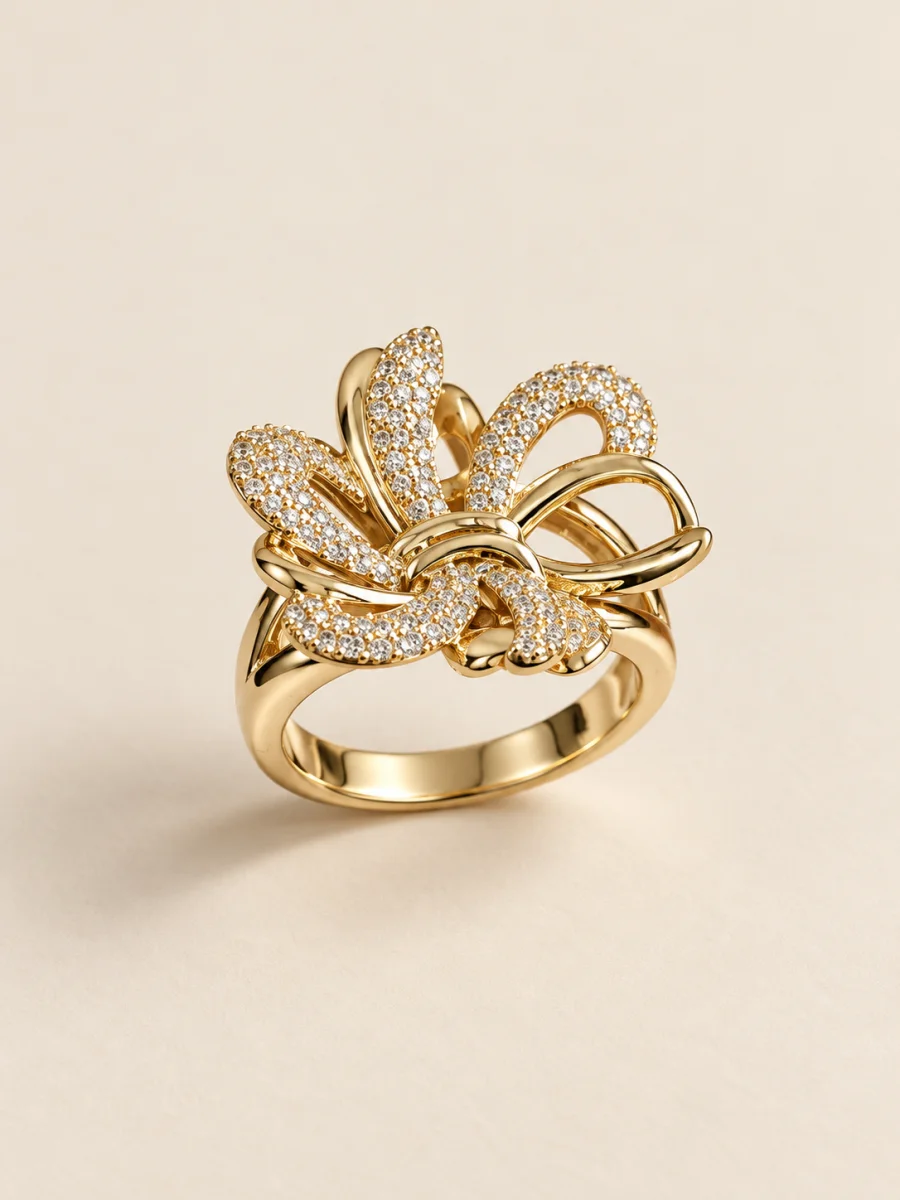 Anel dourado com folhas cravejadas sobre fundo bege
