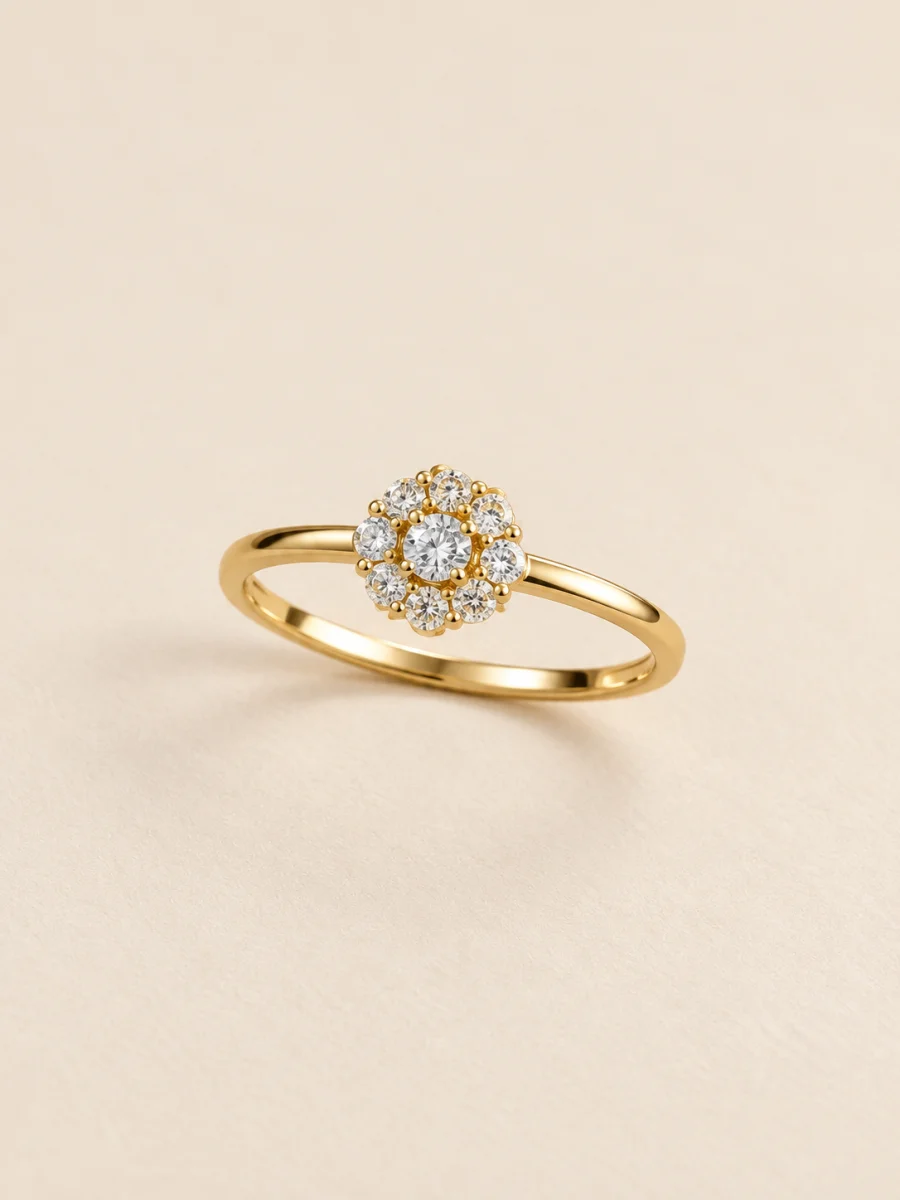 Anel dourado floral com pedras claras sobre fundo bege