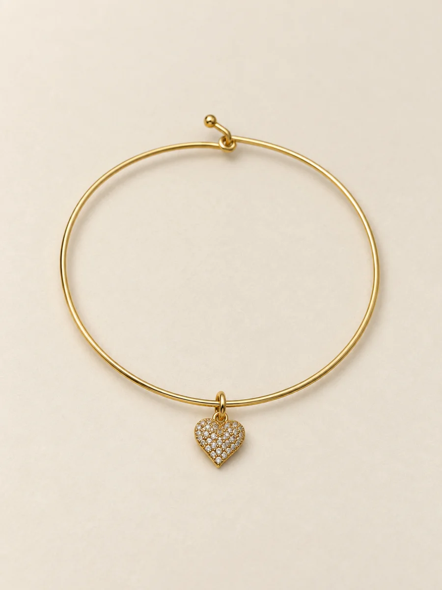 Pulseira dourada com coração cravejado em fundo bege