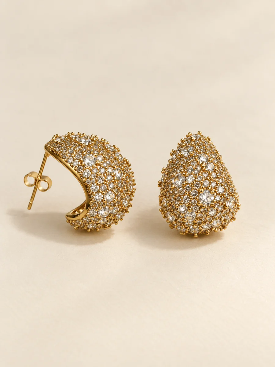Brincos em gota com pedras claras sobre fundo bege