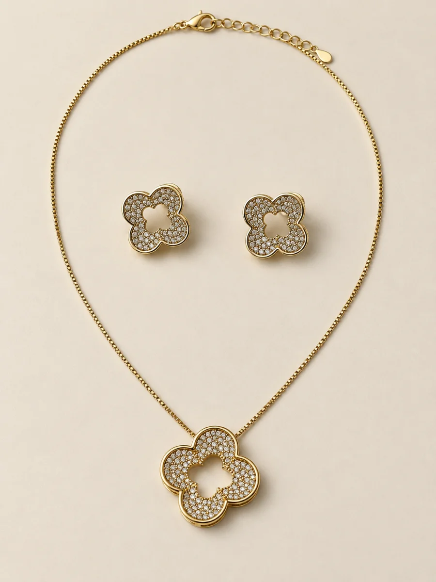 Conjunto dourado de flores vazadas com pedras claras em fundo bege
