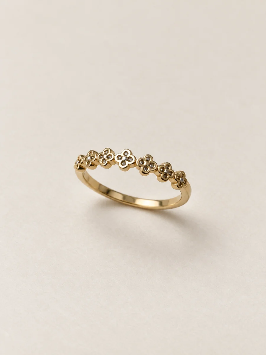 Anel dourado com fileira de flores em fundo bege