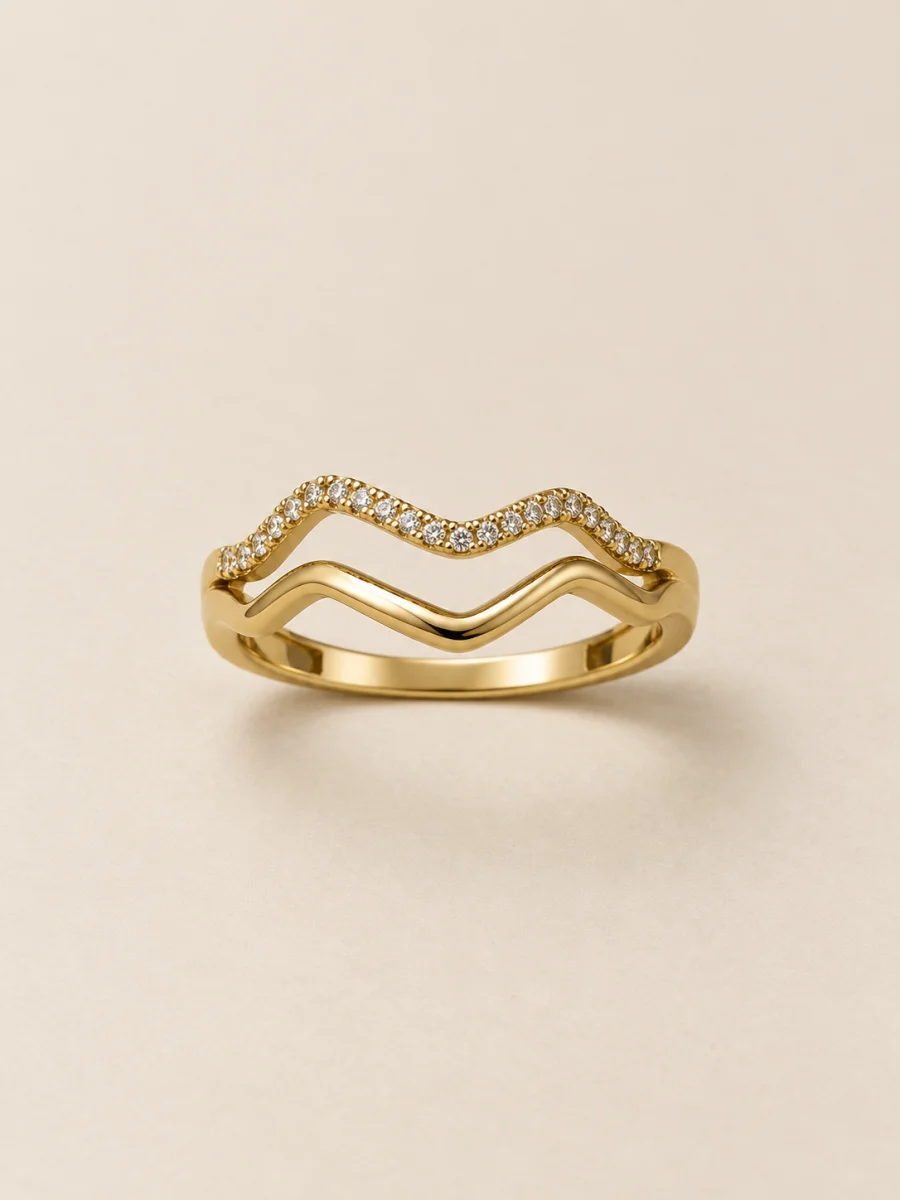 Anel dourado de duas ondas com pedras claras — fundo bege