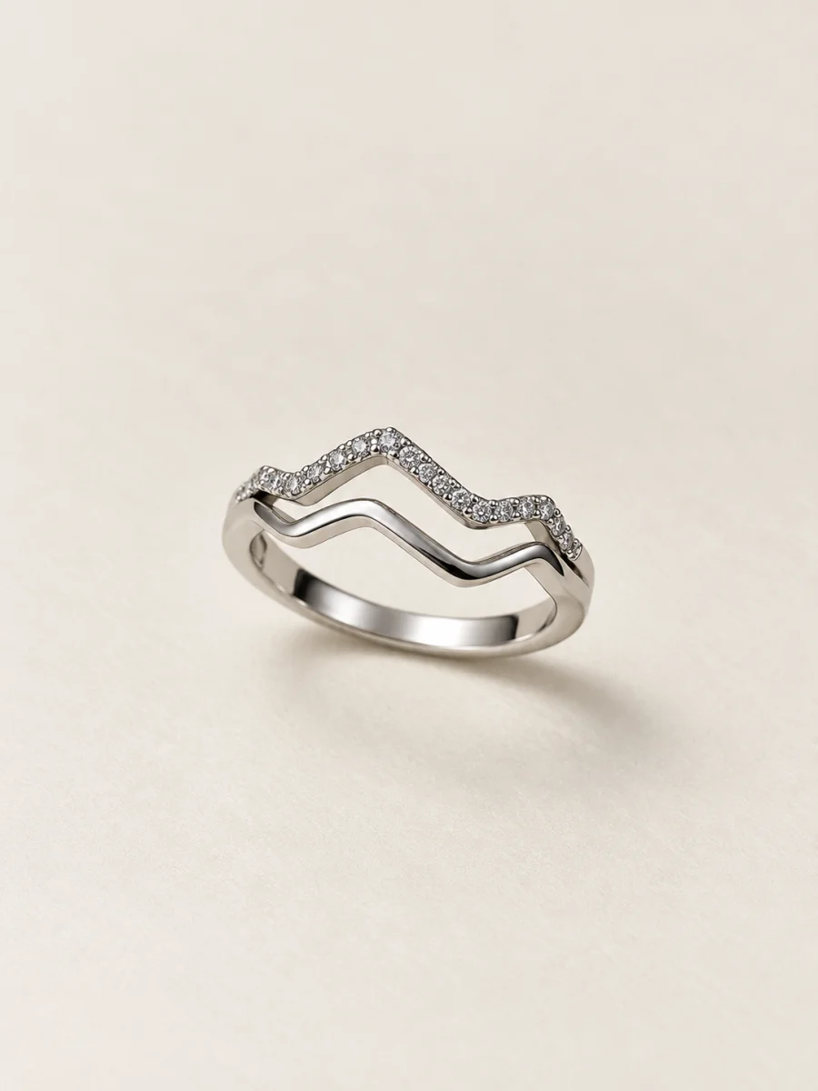 Anel de ouro branco com duas ondas e pedras claras — fundo bege