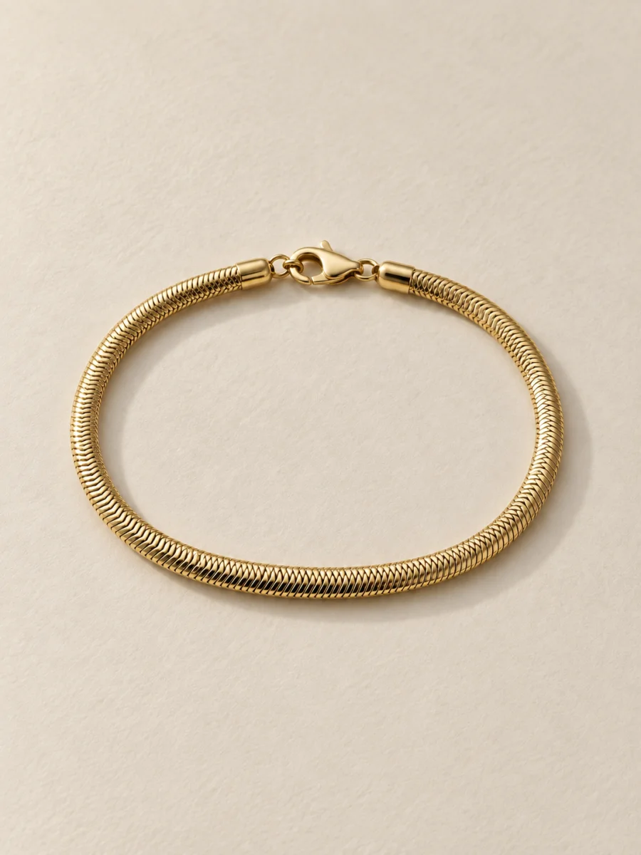 Pulseira malha cobra dourada em fundo bege, padrão 3:4