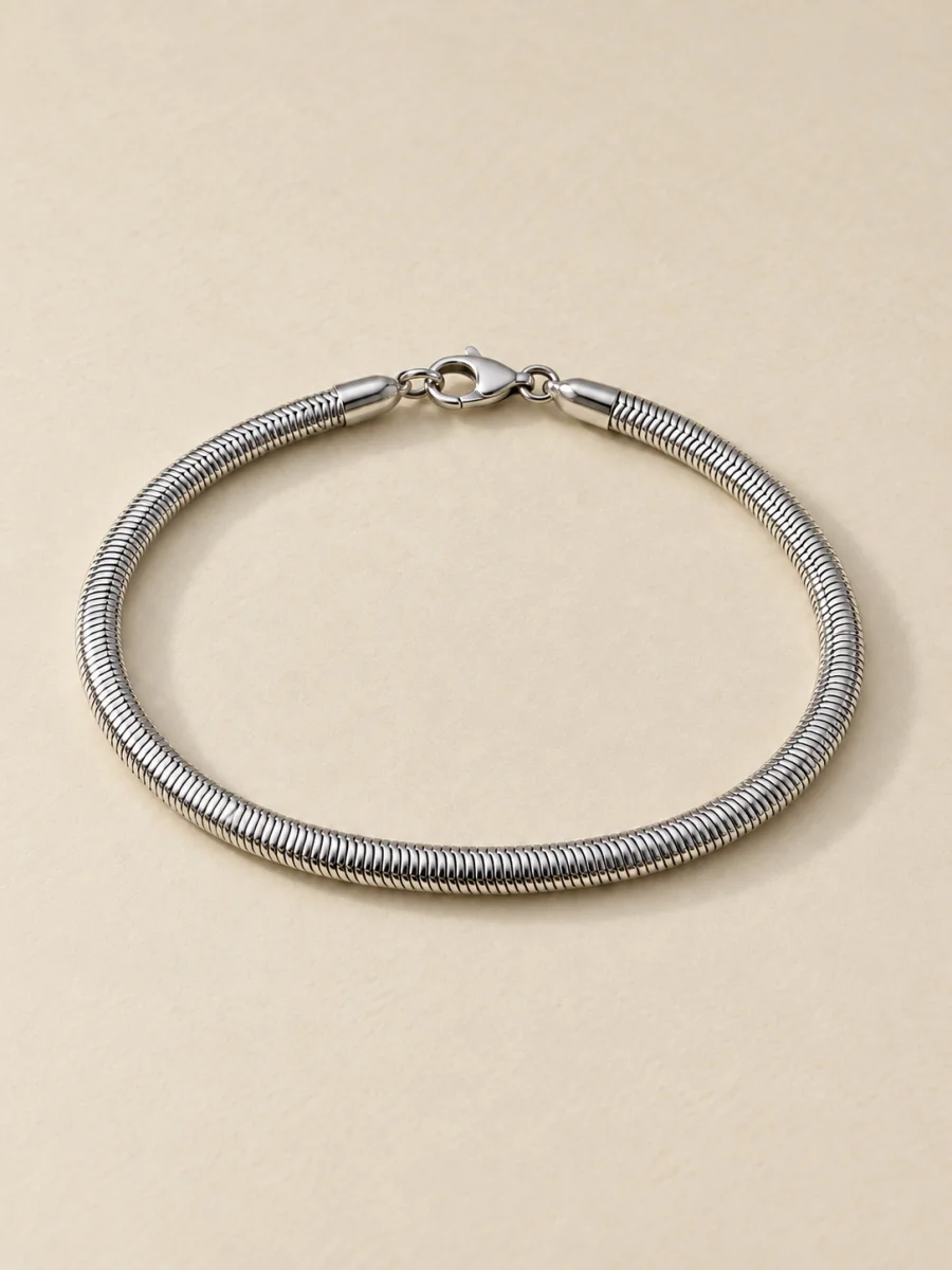 Pulseira malha cobra prateada em fundo bege, padrão 3:4