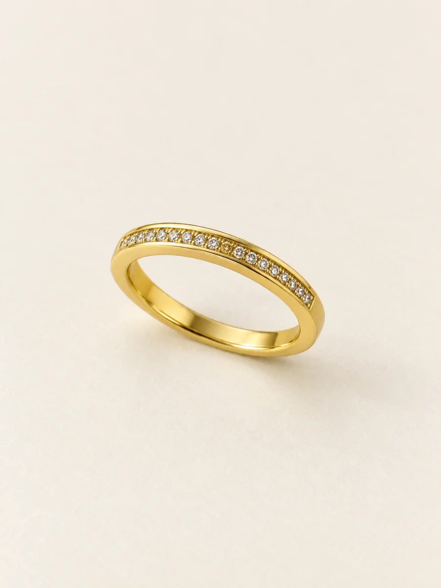 Anel dourado com fileira de pedras claras em fundo bege
