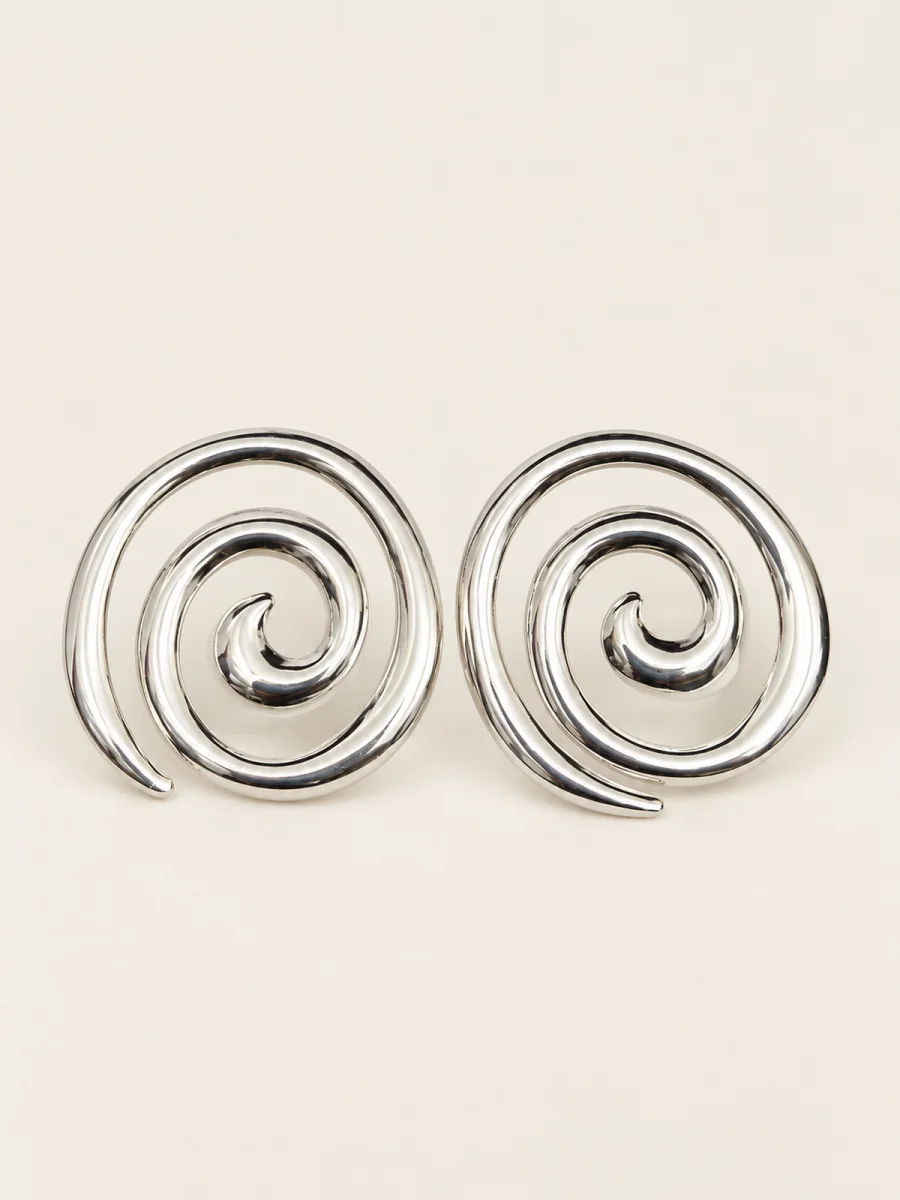 Par de brincos prateados em espiral sobre fundo bege