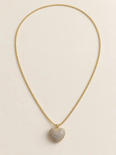 Colar dourado com coração cravejado sobre fundo bege