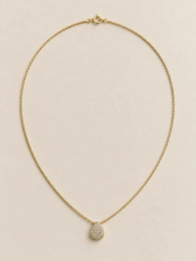 Colar dourado de gota cravejada em fundo bege