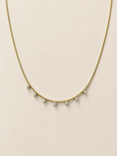 Colar dourado com pedras claras pendentes sobre fundo bege