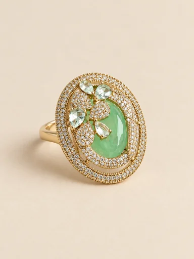Anel dourado oval com pedra verde sobre fundo bege