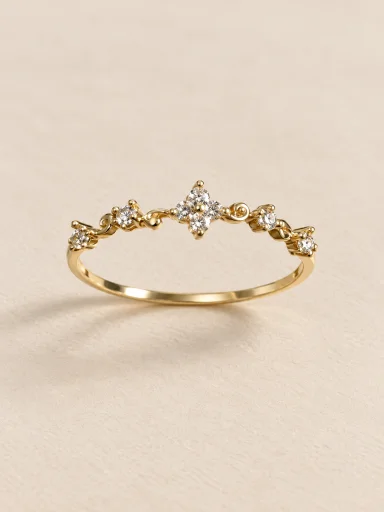 Anel dourado com flores e pedras claras em fundo bege