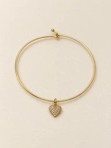 Pulseira dourada com coração cravejado em fundo bege