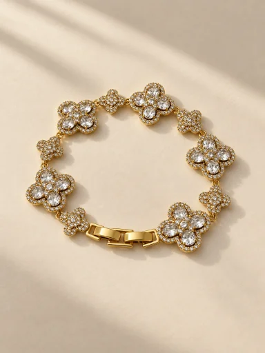Pulseira dourada com flores e pedras claras, fundo bege, padrão 3:4