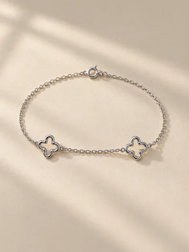 Pulseira prateada com dois trevos em fundo bege, padrão 3:4