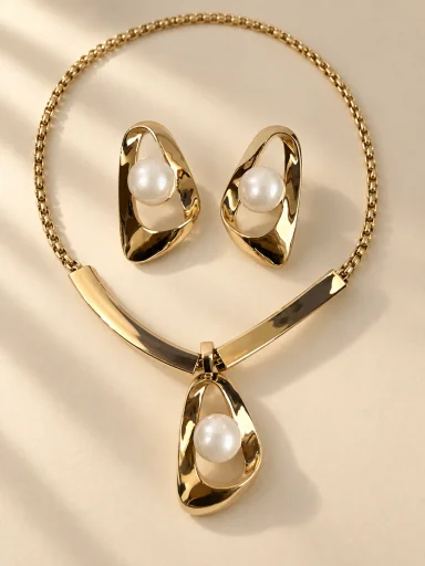 Conjunto dourado de pérolas e elos orgânicos em fundo bege