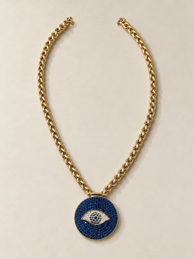Colar dourado de olho grego azul sobre fundo bege