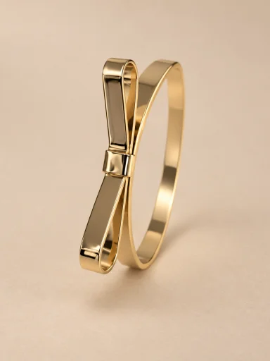 Pulseira dourada com laço escultórico sobre fundo bege
