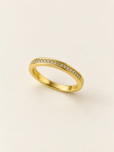 Anel dourado com fileira de pedras claras em fundo bege
